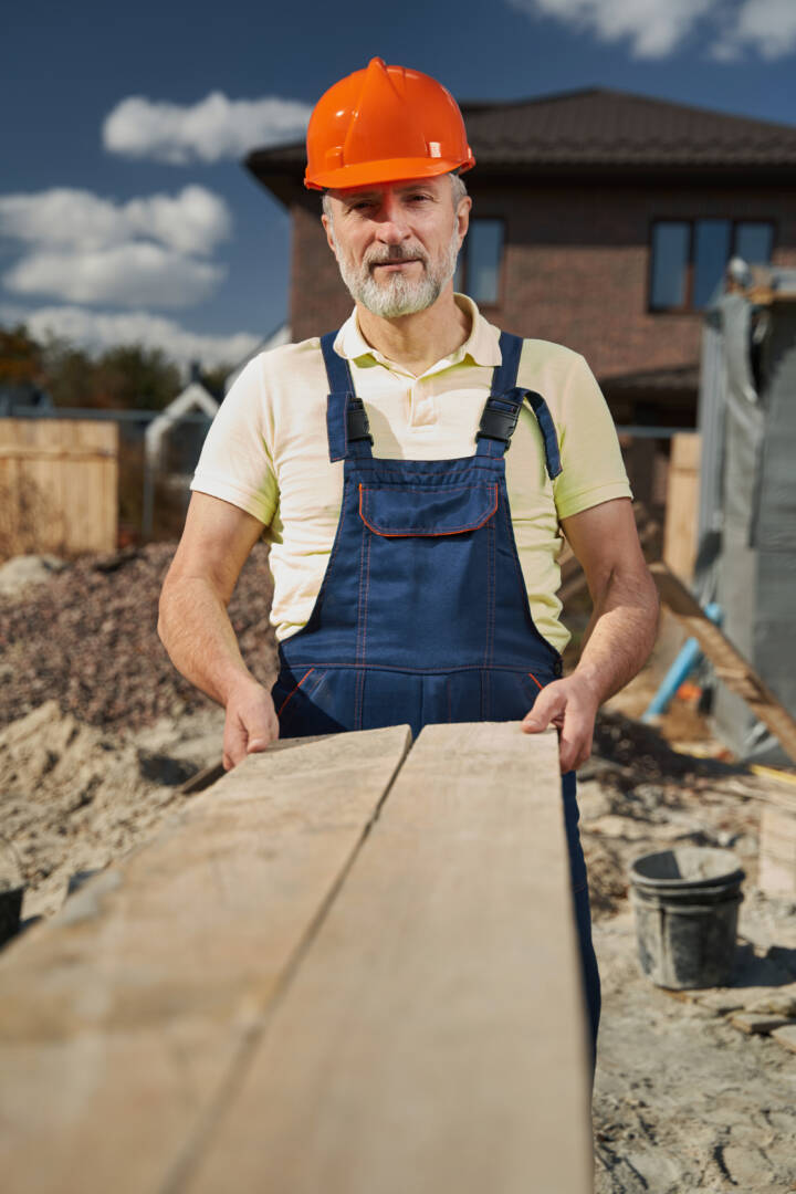 Male construction worker standing in front of camera on building site with outstretched board